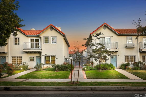 Front view of two-story houses with red roofs and balconies.