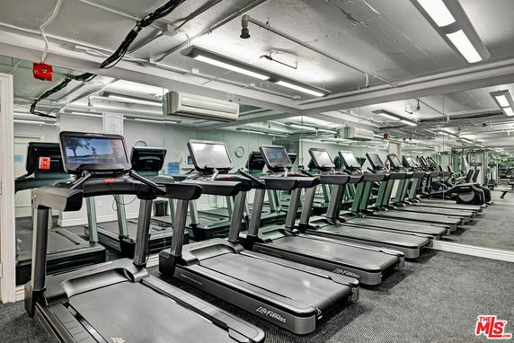 Indoor gym area with multiple treadmills and mirrored walls.