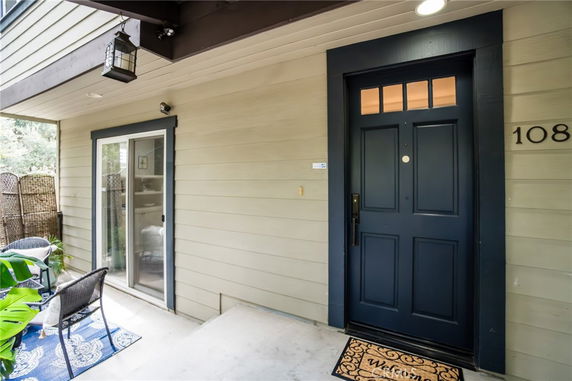 Front view of a house with a black door and sliding glass patio door.