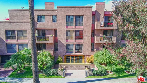 Front view of a multi-story brick building with balconies and large windows.