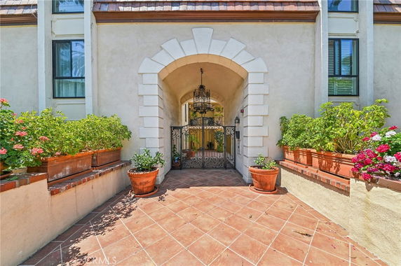 Front view of a house with an arched entrance and decorative plants.