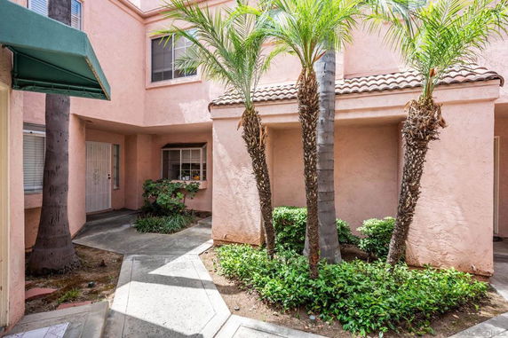 Front view of a two-story house with pink exterior and palm trees.