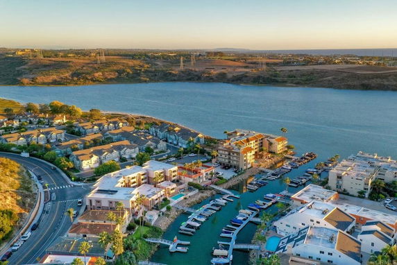 Aerial view of residential area near water with docks and surrounding landscape.