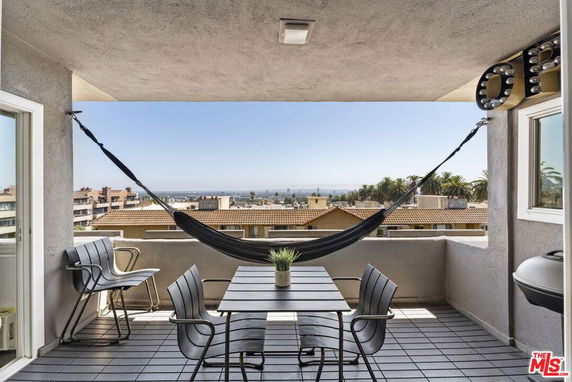 Outdoor balcony with hammock and seating area, offering a panoramic view of the surrounding cityscape and rooftops.
