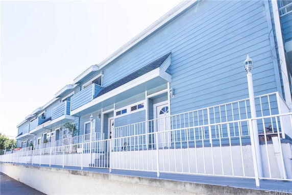 Front view of a multi-story building with blue siding and white railings.