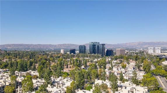 Panoramic view of residential and commercial buildings with mountainous backdrop.
