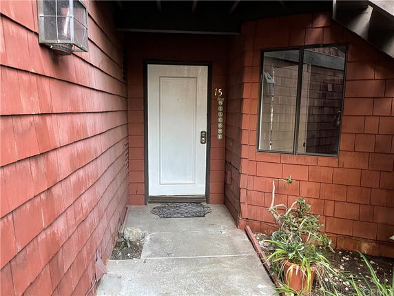 Front view of an entrance to a house with red shingles and a white door.