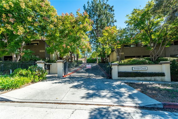 Front view of a residential complex with brown buildings and gated entrance.