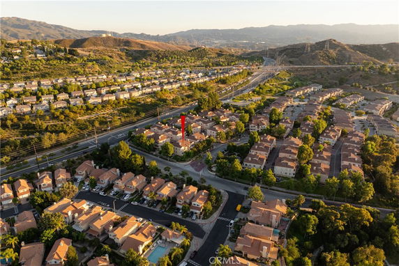Aerial view of a residential neighborhood with multiple houses and roads, surrounded by hills.
