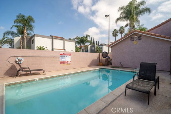 Outdoor swimming pool area with lounge chairs and surrounding fence.