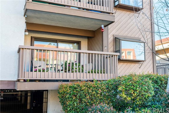 Front view of a multi-story building with a balcony and wooden railing.