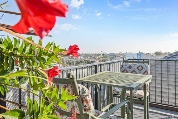 Balcony with table and chairs, overlooking the cityscape.