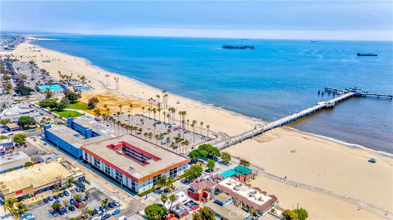 Panoramic view of a beachside area with buildings, a pier, and the ocean.