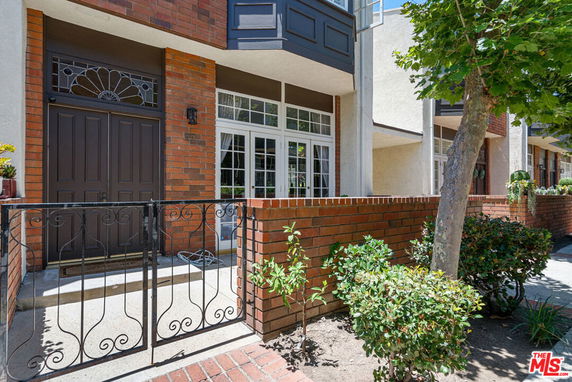 Front view of a townhouse with a brick facade and gated entrance.
