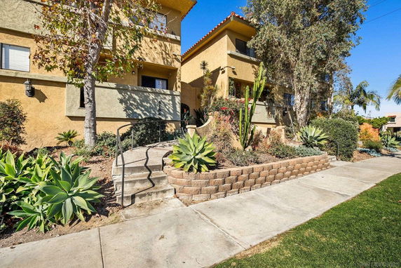 Front view of a two-story building with a landscaped garden and a walkway.