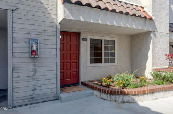 Front view of a house with a red door and a small garden area.