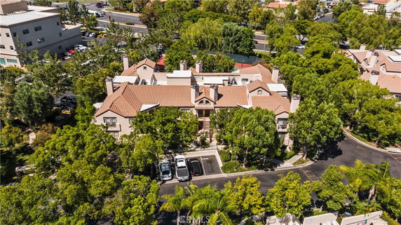 Aerial view of a large residential building with a complex roof design and surrounded by trees.