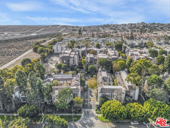 Aerial view of a residential neighborhood with multiple buildings surrounded by trees.