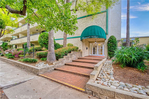 Front view of a building with multiple balconies and a green awning over the entrance.