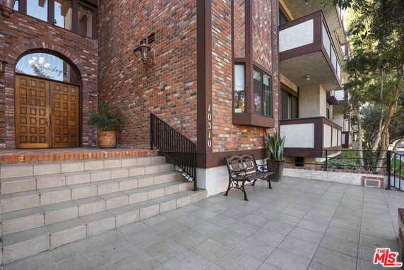 Front view of a building with brick facade, wooden door, and balcony.