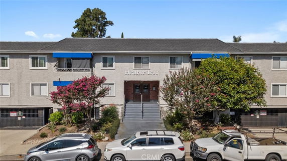 Front view of a multi-story apartment building with cars parked in front.