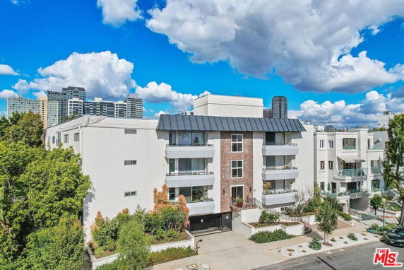 Front view of a multi-story residential building with balconies and a gated entrance.