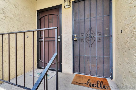 Front view of a residential entrance with metal security door and welcome mat.