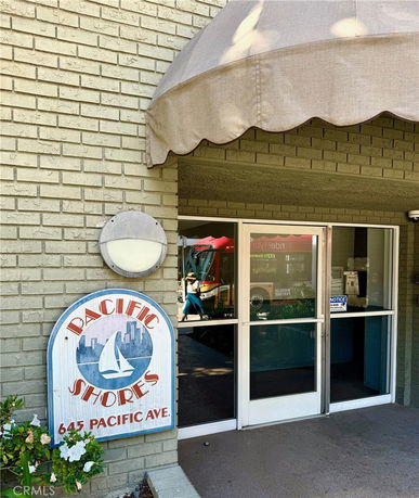 Front view of a building entrance with a canopy and a signboard reading 'Pacific Shores, 645 Pacific Ave.'