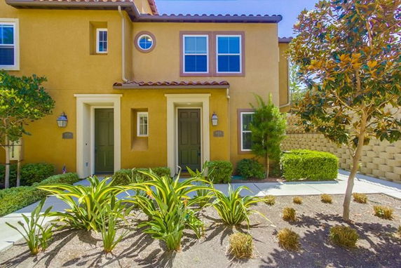 Front view of a two-story townhouse with two entrances and garden area.