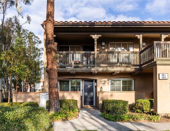 Front view of a two-story house with a balcony and tan exterior.