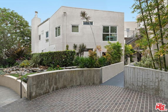 Front view of a modern multi-story building with a paved entrance and landscaped garden.