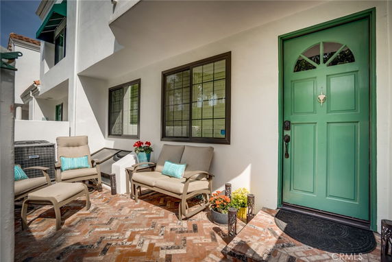 Front view of a house with a green door and patio seating area.