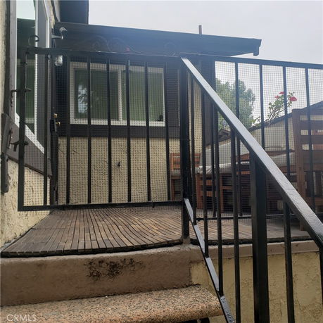 Front view of a house with a staircase leading to a gated entry.