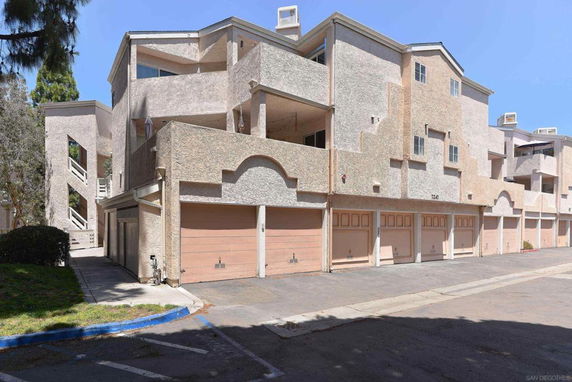 Front view of a multi-story residential building with multiple garages on the ground floor.