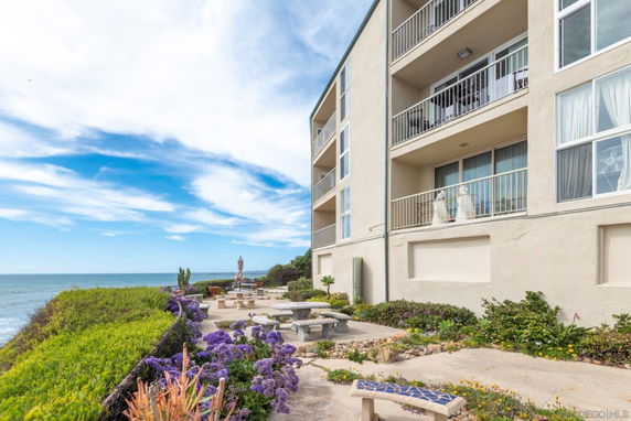 Side view of a multi-story building with balconies by the ocean.