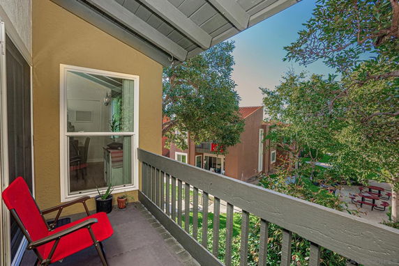 Balcony view from a building overlooking other residential structures and trees.