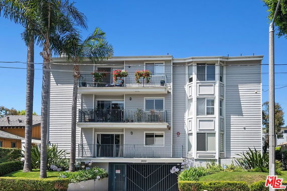 Front view of a multi-story residential building with balconies and large windows.