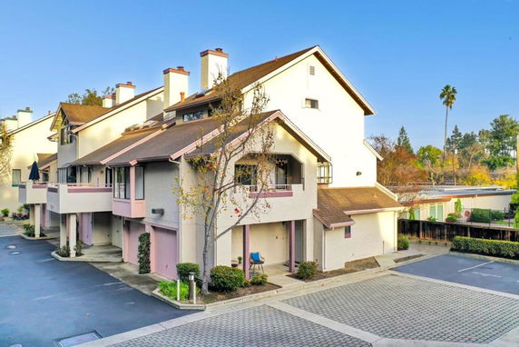 Corner view of a multi-story townhouse with a sloped roof and balconies.