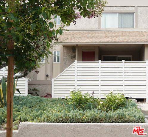 Front view of a house with a white fence and small garden.