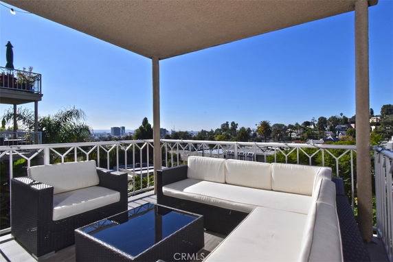 Outdoor terrace with seating and a view of the city and greenery.
