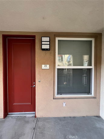 Front view of a residential unit with a red door and window with blinds.
