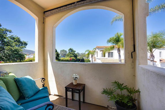View from a balcony showing nearby houses with palm trees.