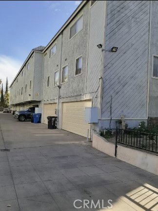 Side view of a multi-story building with garages at the ground level.