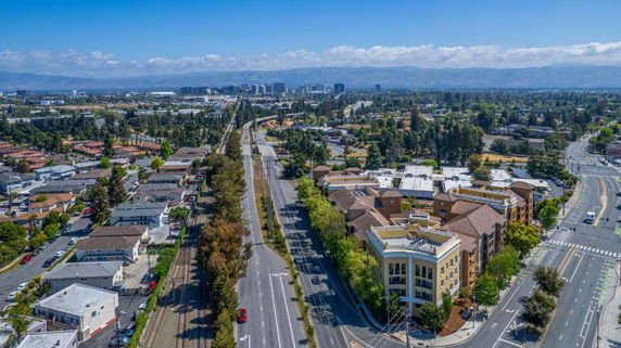 Panoramic view of buildings, roads, and surrounding areas with distant mountains.
