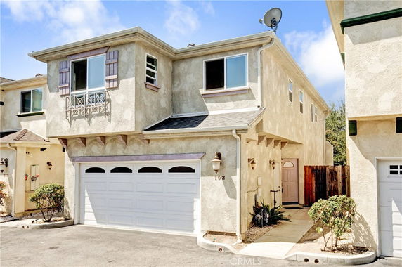 Front view of a two-story house with a garage and a small balcony.