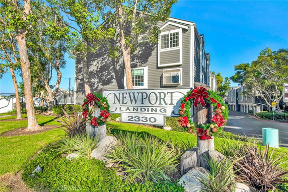 Front view of a multi-story building with a sign reading 'Newport Landing 2330' and decorative wreaths.
