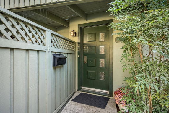 Front view of a house entrance with a decorative green door and wooden lattice fence.