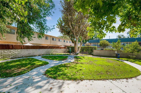 Outdoor view of residential area with a pathway, a tree, and adjacent buildings.