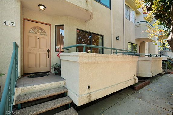 Front view of a multi-story house with a beige exterior and steps leading to the entrance.