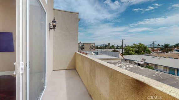 View from a small outdoor balcony overlooking nearby buildings and landscape.